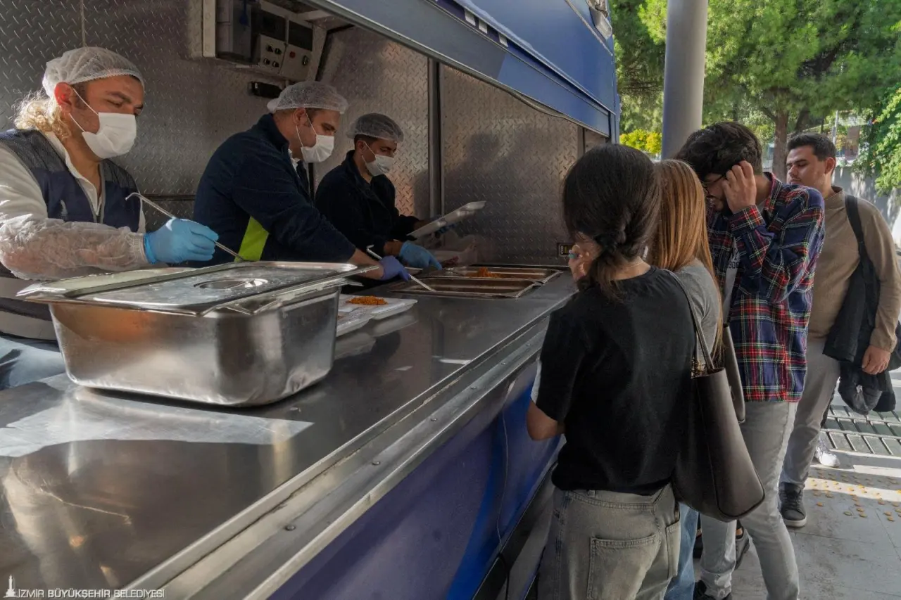 İzmir Büyükşehir Belediyesi’nin üniversite öğrencilerine yönelik ücretsiz sıcak yemek dağıtımı yeni öğrenim yılında da aksatılmıyor. Altı devlet üniversitesinin kampüsü ve yakınında anne eli lezzetinde üretilen yemeklerle gençlerin bütçelerine katkı sağlanıyor.
